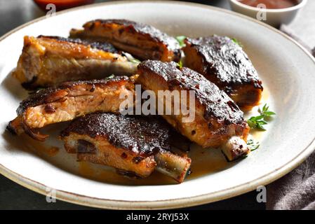 Nahaufnahme von geschnittenen Schweinerippchen auf weißem Teller. Stockfoto