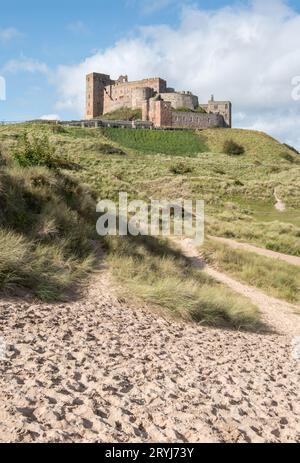 Bamburgh Castle an der nordöstlichen Küste Englands in Northumberland von den Sanddünen am Ufer aus gesehen. Stockfoto