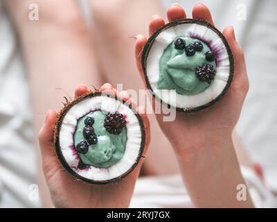 Zwei coconut Hälfte spirulina Smoothie in Frau Hände Stockfoto