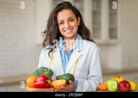 Porträt einer lächelnden Ernährungswissenschaftlerin mit Teller mit frischen Früchten, Arbeit in der Gewichtsabnahme-Klinik, lächelnd in die Kamera Stockfoto