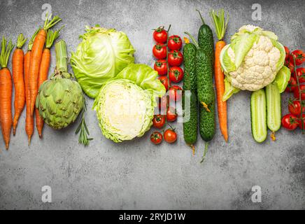 Frisches, gemischtes Bio-Gemüse in einer Reihe auf dem rustikalen grauen Steintisch mit Blick von oben angeordnet. Vegetarische Lebensmittel Hintergrund und gesund V Stockfoto