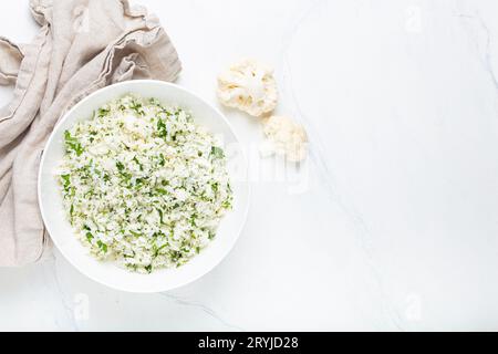 Roher Blumenkohlreis oder Couscous mit Dill in weißer Schüssel, gesunde kohlenhydratarme Gemüsebeilage für Keto-Ernährung und Gesundheit Stockfoto