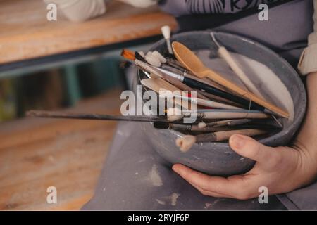 Bürsten in einer Schüssel in den Händen des Künstlers, Nahaufnahme. Stockfoto