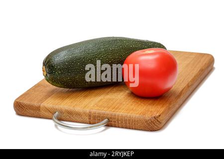 Tomate und Zucchini auf dem Holzschneidebrett. Stockfoto