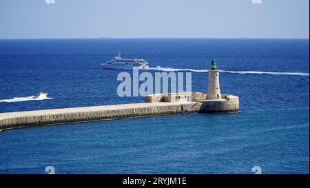 St. Elmo Breakwater Lighthouse, Grand Harbour, Valletta, Malta. Gemauerter Turm mit grüner Laterne aus dem Jahr 1908. Fähre nach Sizilien, Italien. Stockfoto