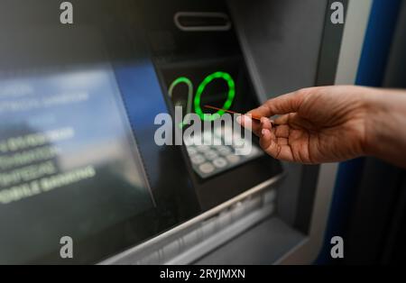 Frau zieht Geld mit einer Karte von einem Geldautomaten ab. Stockfoto