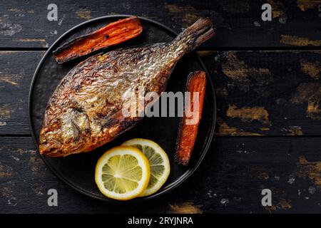 Gebratener dorado-Fisch mit gegrilltem Gemüse und Zitrone auf einem alten Holztisch. Draufsicht. Leerzeichen kopieren Stockfoto