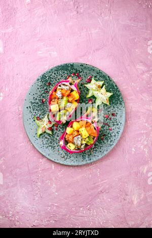 Traditioneller Obstsalat am Valentinstag mit exotischen Fruchtstücken, serviert in DrachenObstschalen und dekoriert mit Sternfrüchten auf A Stockfoto