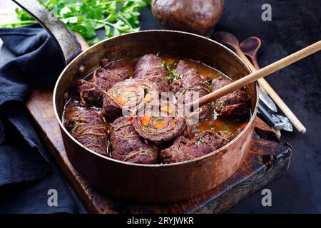 Traditionelle langsam gekochte deutsche Wagyu-Rinderrouladen mit Gemüse und Speck, serviert in scharfer Soße als Nahaufnahme in Kupfer Stockfoto