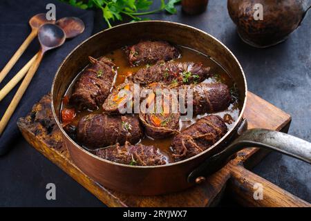 Traditionelle langsam gekochte deutsche Wagyu-Rinderrouladen mit Gemüse und Speck, serviert in scharfer Soße als Nahaufnahme in Kupfer Stockfoto