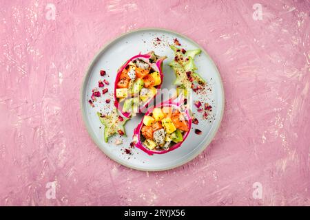 Traditioneller Obstsalat am Valentinstag mit exotischen Fruchtstücken, serviert in DrachenObstschalen und dekoriert mit Sternfrüchten auf A Stockfoto