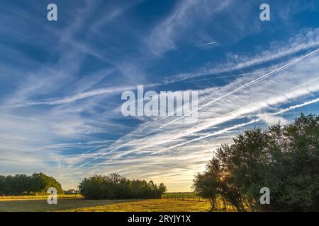 Mehrere Kondensstreifen am frühen Morgenhimmel auf vielbefahrenen Verkehrsflugstrecken über Zentralfrankreich. Stockfoto