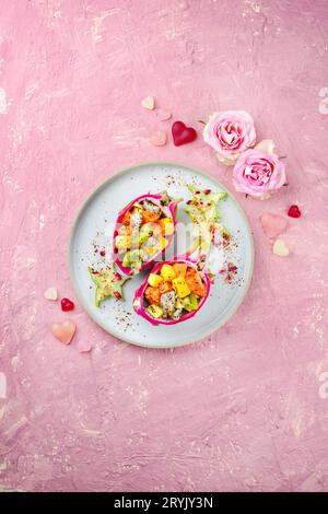 Traditioneller Obstsalat am Valentinstag mit exotischen Fruchtstücken, serviert in DrachenObstschalen und dekoriert mit Sternfrüchten auf A Stockfoto