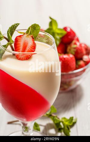 Kirsch- und Milchgelee im Glas, dekoriert mit Minzblättern. Stockfoto