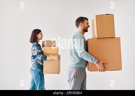 Profilansicht eines jungen Paares mit Kartonkisten, die zu einem neuen Haus auf weißem Hintergrund ziehen Stockfoto