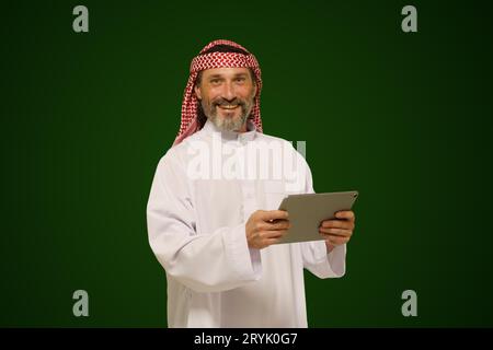 Arabischer muslimischer Mann hält ein digitales Tablet. Konzept der Online-Kommunikation und der globalen Verbindung durch Technologie. Stockfoto