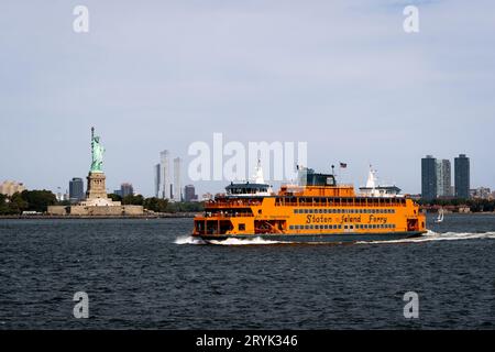 NEW YORK, USA - 16. SEPTEMBER 2023. Die Fähre von Staten Island, die an Liberty Island vorbei fährt, mit der Freiheitsstatue von L nach Staten Island Stockfoto