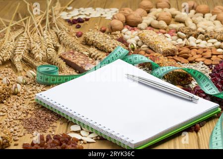 Ausgewogener veganer Snack, Protein-Müsliriegel. Nüsse, Samen, Getreide Notizbuch, Stift, Maßband auf hölzernem Hintergrund. Wiegeless-Konzept. Draufsicht, Clos Stockfoto