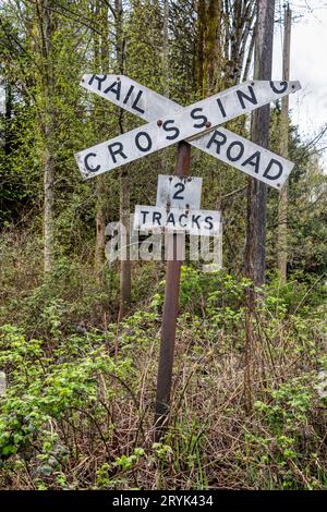 Altes Zeichen der Eisenbahnüberquerung auf Frühlingsbäumen Hintergrund Stockfoto