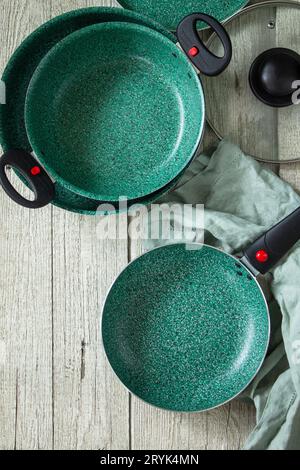 Neues Set leere Pfanne grün mit Keramik coatingon auf einem rustikalen Küchentisch. Draufsicht flach lay Hintergrund. Speicherplatz kopieren. Stockfoto