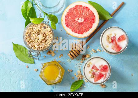 Vegan gesundes Frühstück. Müsli mit griechischem Joghurt, Honig und Grapefruit in einem Glas. Draufsicht flach lay Hintergrund. Stockfoto