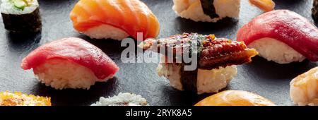 Sushi-Panorama. Nigiri mit Aal, Thunfisch, Lachs auf schwarzem Hintergrund Stockfoto