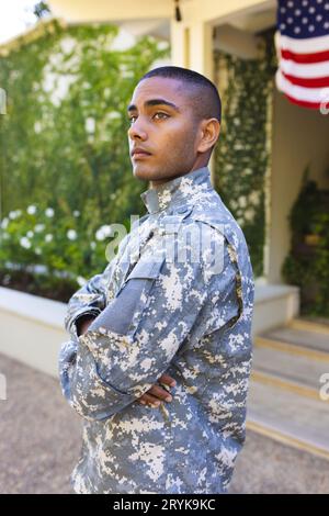 Ein männlicher amerikanischer Soldat mit Militäruniform, der vor dem Haus steht und wegsieht Stockfoto