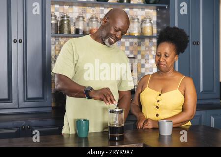 Glückliches Senior-afroamerikanisches Paar, das in der Küche Kaffee zubereitete Stockfoto