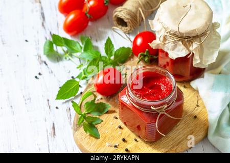 Tomatenmark, Haushaltung. Tomatensauce aus reifen Tomaten auf einer Holzplatte. Speicherplatz kopieren. Stockfoto