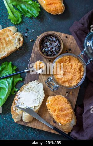 Sandwiches mit Butter und gesalzenem Kaviar auf einer Arbeitsplatte aus dunklem Stein. Draufsicht flach lay Hintergrund. Stockfoto