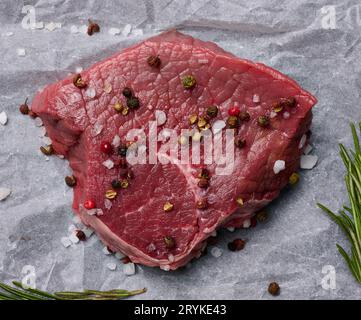 Rohes Rindfleisch mit Gewürzen liegt auf einem weißen Stück Pergamentpapier, Draufsicht Stockfoto