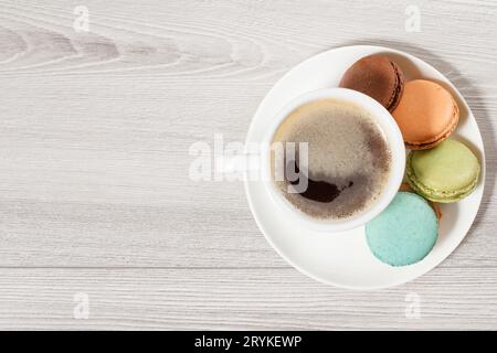 Tasse Kaffee und leckere Macarons Kuchen in verschiedenen Farben auf einem weißen Teller. Stockfoto