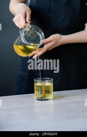 Das Mädchen gießt Wachs in Glasgläser mit Dochten. Stockfoto