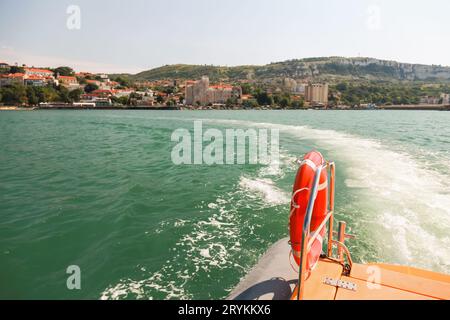 Rotes Rettungsboot, das an einem sonnigen Tag an Stahlgeländern eines Rettungsbootes hängt Stockfoto