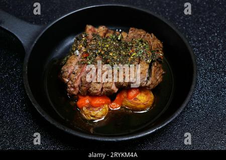 spanische Chimichurri-Rindersteaks mit Kartoffeln und scharfer brava-Sauce auf schwarzem Hintergrund Stockfoto