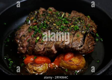 chimichurri-Rindersteaks und Kartoffeln, scharfe spanische brava-Sauce auf schwarzem Hintergrund Stockfoto