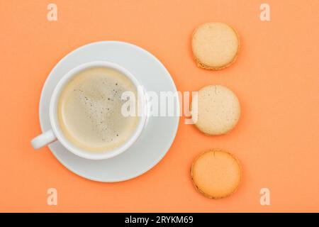 Tasse Kaffee und leckere Macarons Kuchen auf dem pfirsichfarbenen Hintergrund Stockfoto
