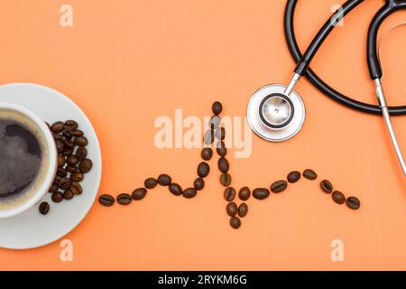 Tasse Kaffee auf einer Untertasse mit gefalteten Kaffeebohnen in Form eines Kardiogramms Stockfoto