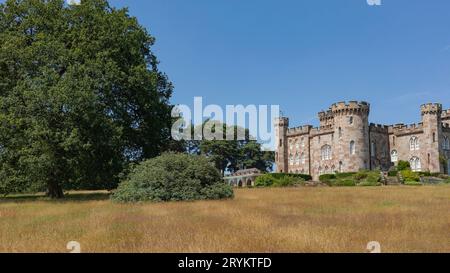 Cholmondeley, West Cheshire, Vereinigtes Königreich - 18. Juli 2021 - Cholmondeley Castle in der Sommersonne auf einem Hügel mit trockenem Gras Stockfoto