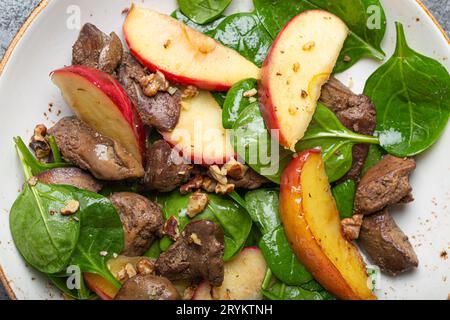 Nahaufnahme gesunder Salat mit eisenreichen Zutaten Hühnerleber, Äpfel, frischer Spinat und Walnüsse auf weißer Keramikplatte fro Stockfoto