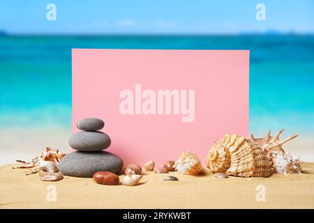 Einladung oder Grußkarte Mockup mit Muscheln und Steinpyramide am Sommersandstrand Stockfoto