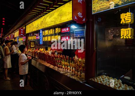 Chinesen kaufen abends Süßigkeiten aus einer Straßenkonditorei. Imbiss Street Food Markt Peking china Stockfoto