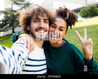 Lächelndes junges Paar, das ein Selfie in einem Stadtpark macht. Glückliches heterosexuelles Paar, Freundschaft Stockfoto