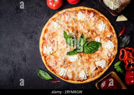 Pizza mit Meeresfrüchtegarnelen, Lachs und Zutaten auf schwarzem Hintergrund Stockfoto