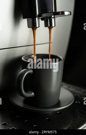 Espresso wird aus einer Kaffeemaschine zu Hause in eine Espressomaschine gegossen. Stockfoto