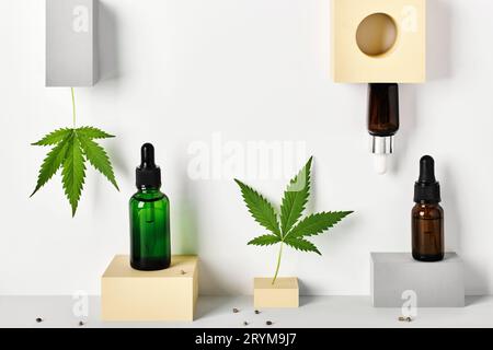 Verschiedene Glasflaschen mit CBD-Öl und Cannabisblättern auf abstrakten geometrischen Podesten. CBD-Öl-Konzept für Kosmetik Stockfoto