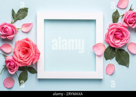 Arrangement schöner Rosen. Weißer Papierrahmen auf blauem Pastellhintergrund. Muttertag, Valentinstag, Geburtstagskarte Stockfoto