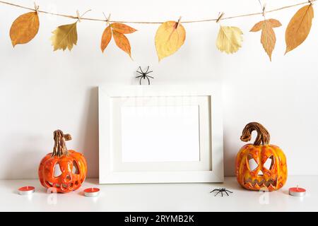 Halloween Komposition mit Keramik Kürbisse, florale Girlande und Rahmen auf Tischwand Hintergrund. Grußkartenvorlage Stockfoto