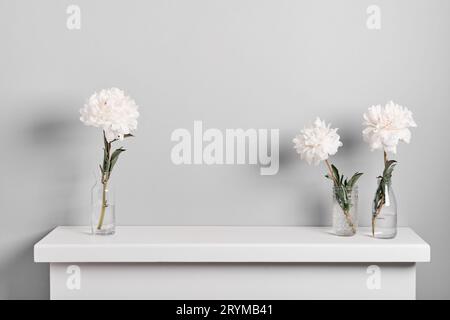 Elegante weiße Pfingstrosen-Blumenarrangements am Kamin. Minimalistische Einrichtung mit Blumenmuster Stockfoto