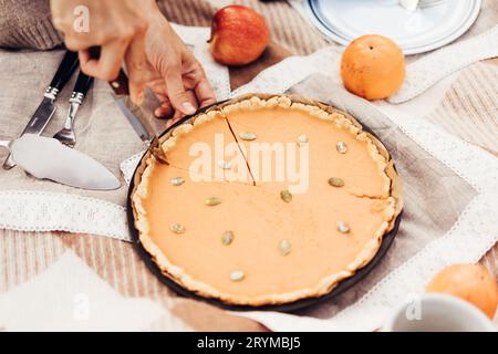 Nahaufnahme Frau schneidet Kürbiskuchen beim Herbst Picknick Stockfoto